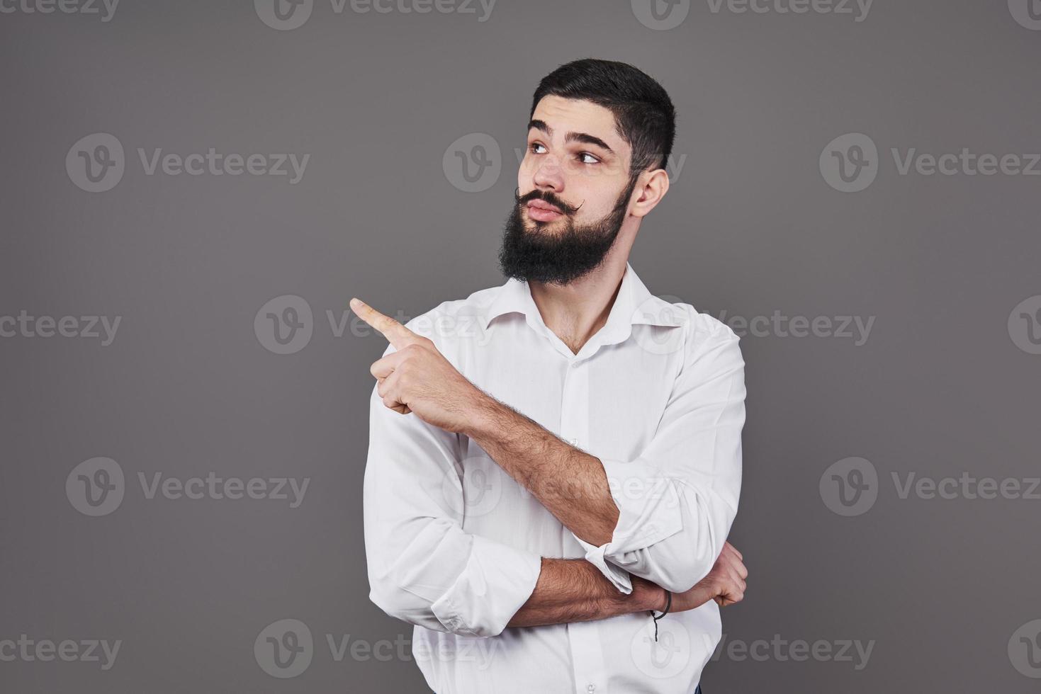 alegre guapo mostrando la dirección y señalando con el dedo foto