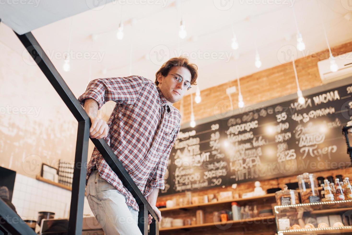 Thoughtful young man is sitting in confectionery shop. She is drinking coffee while waiting for someone photo