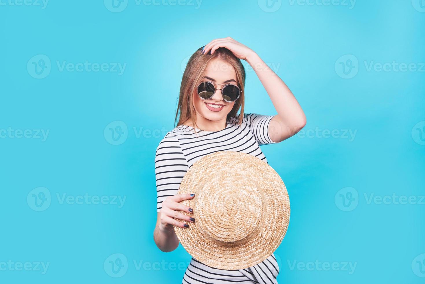 Attractive girl in a white and black stripes, hat, sunglasses, emotionally opened mouth on a bright blue background with a perfect body. Isolated. Studio shot photo