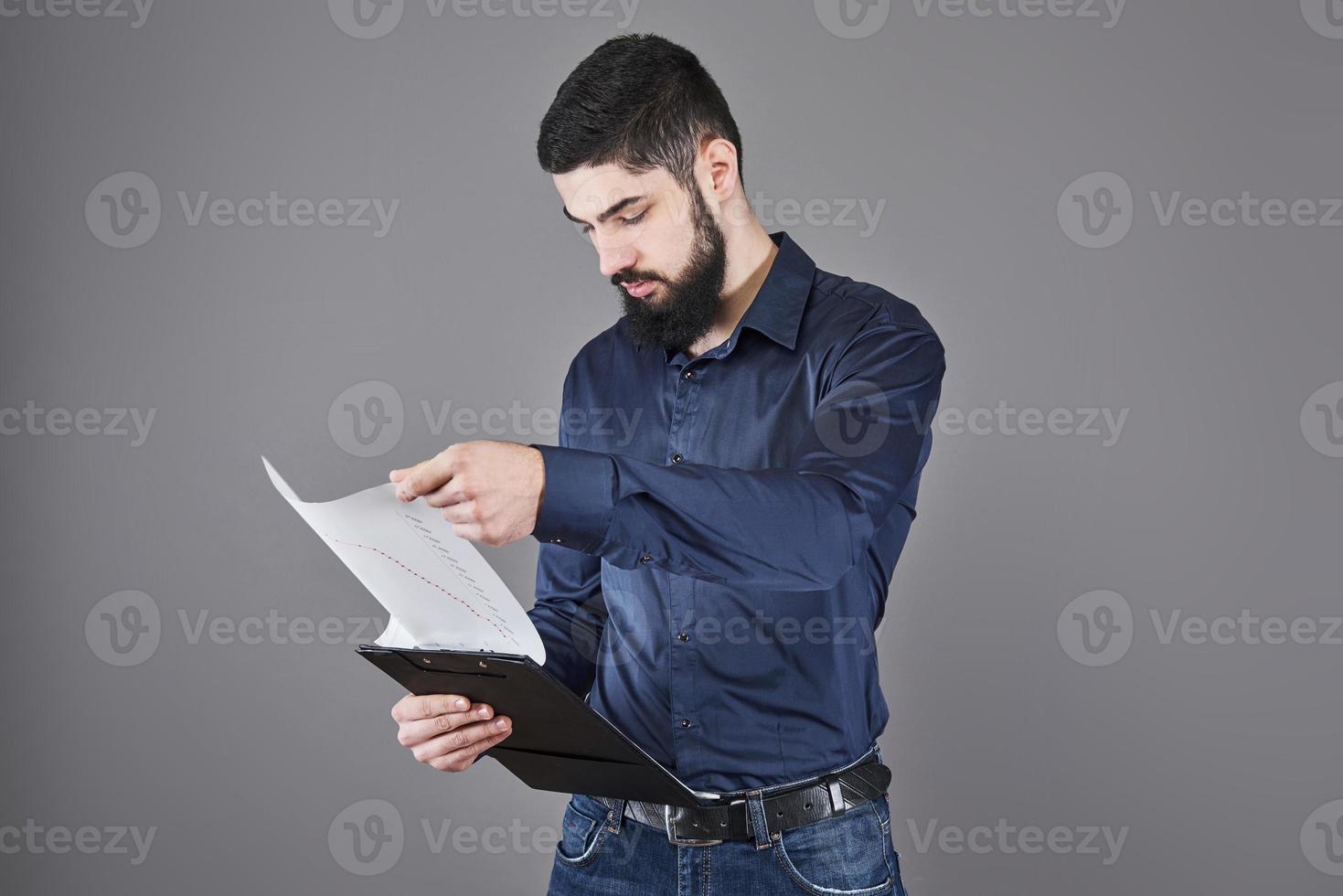 concentrado, joven, atractivo, hombre de negocios, en, camisa azul, planificación, y, escritura, en, portapapeles foto