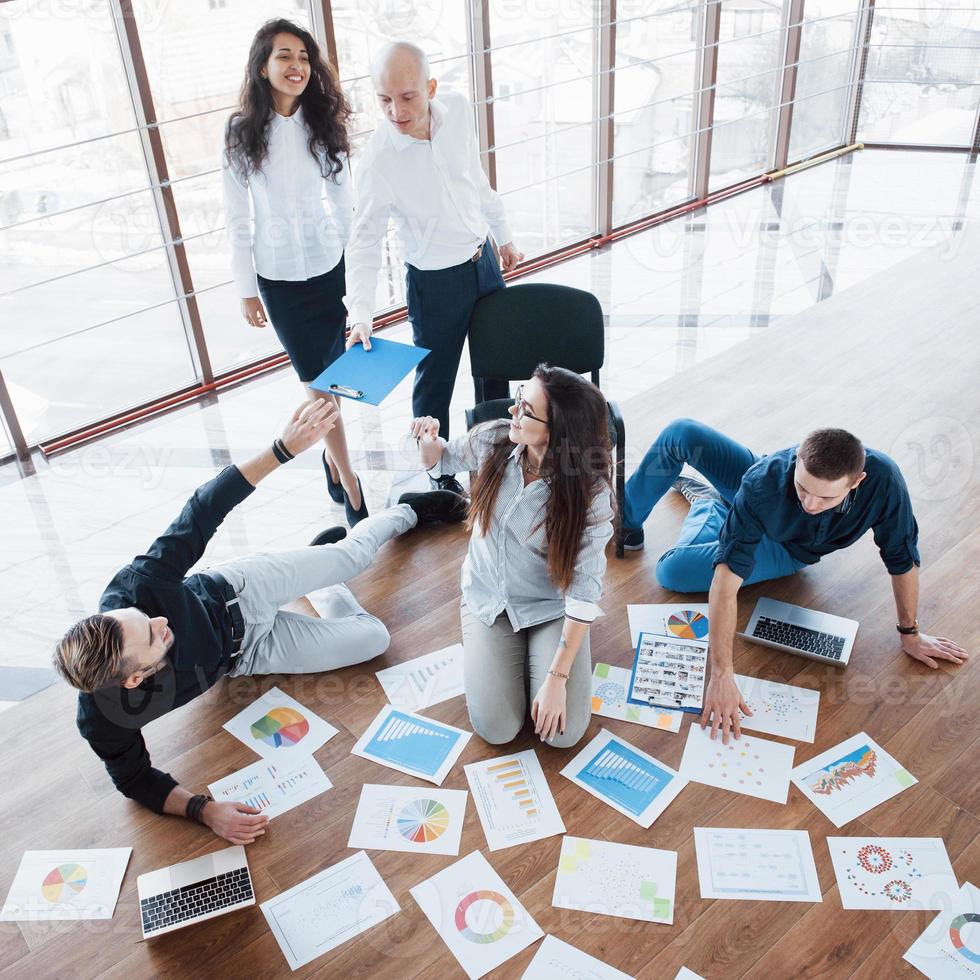 planificación de la estrategia en conjunto. equipo de negocios mirando papeles en el piso con el gerente apuntando a una idea. logro corporativo de cooperación. dibujo de diseño de planificación. concepto de trabajo en equipo foto