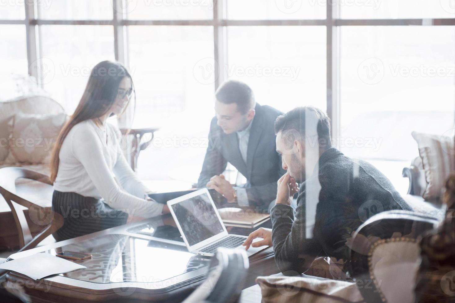 bienvenidos a bordo dos hombres guapos dándose la mano con una sonrisa en la oficina con sus compañeros de trabajo. joven equipo de compañeros de trabajo haciendo una gran discusión de negocios en la moderna oficina de coworking. concepto de personas de trabajo en equipo foto