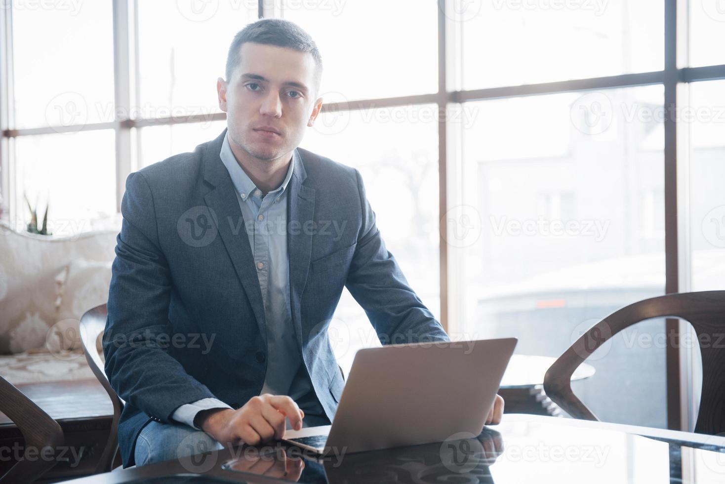 Conceived young man working on laptop while sitting at his working place in office photo