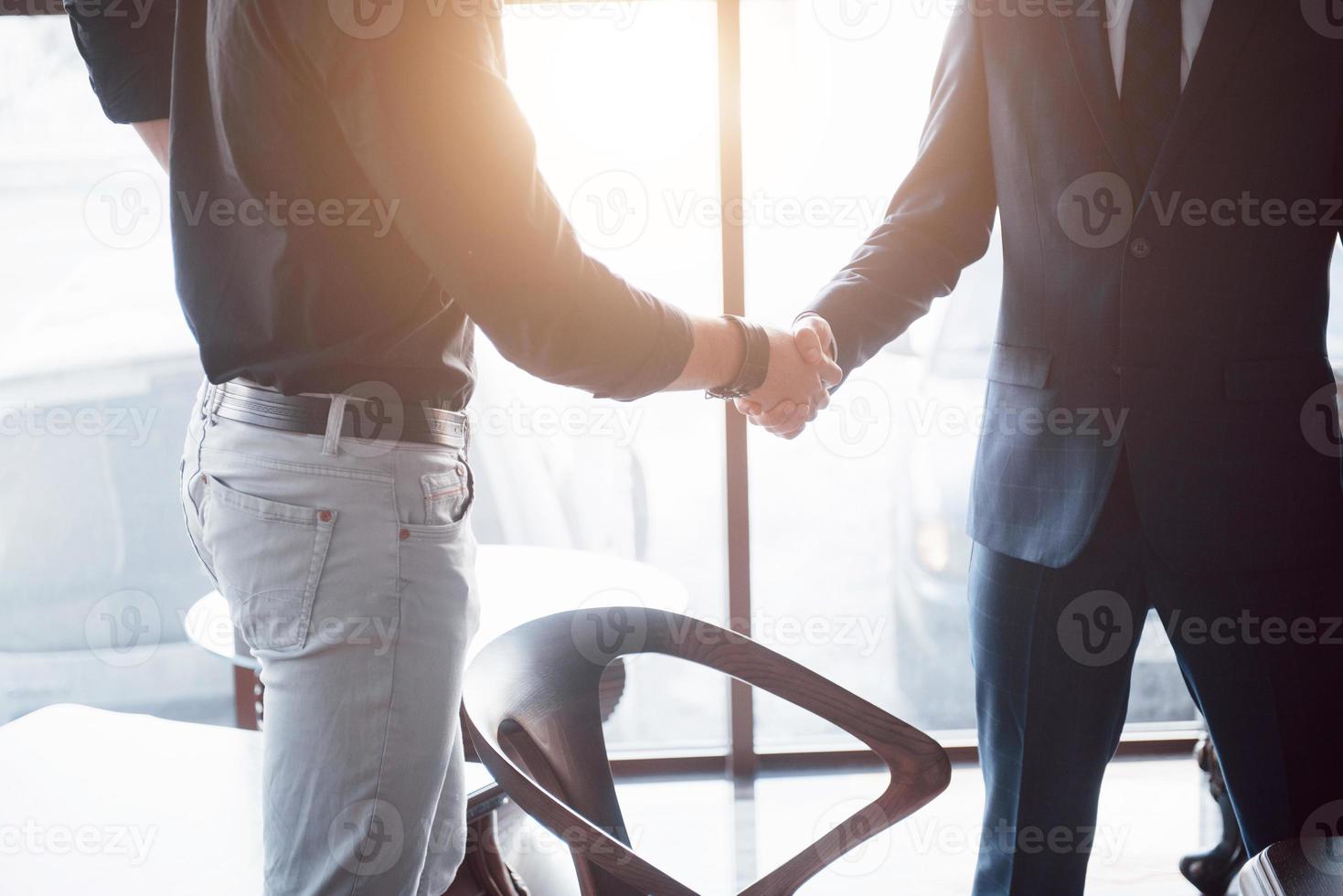 dos hombres de negocios confiados dándose la mano durante una reunión en la oficina, el éxito, el trato, el saludo y el concepto de socio. foto