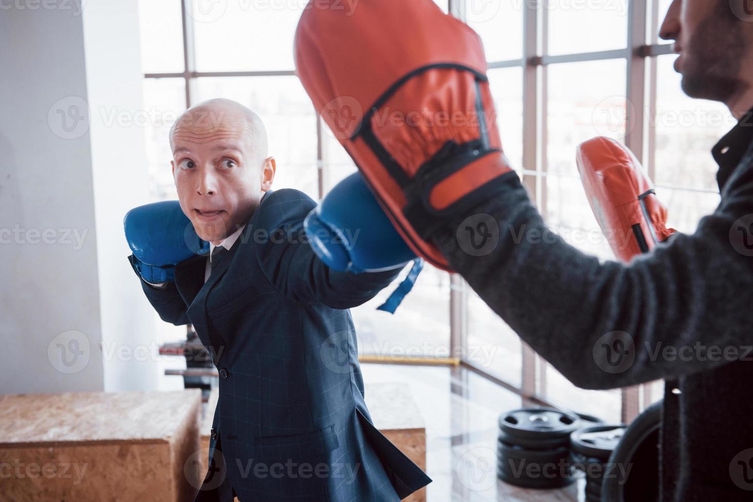 An angry bald businessman beats a boxing pear in the gym. concept of anger management photo