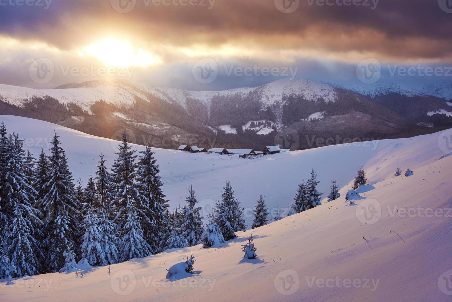 majestuosa puesta de sol en un pequeño pueblo en una colina nevada bajo ucraniano. pueblos en las montañas en invierno. hermoso paisaje de invierno. Cárpatos, Ucrania, Europa foto