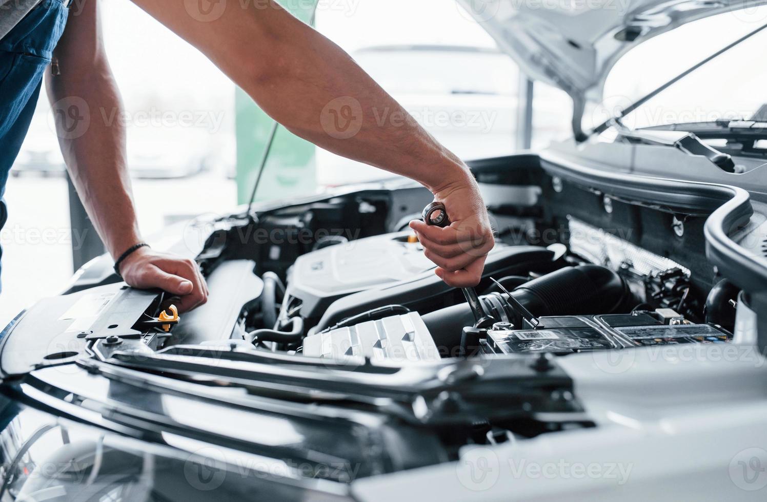 Here we go. Process of repairing car after accident. Man working with engine under the hood photo