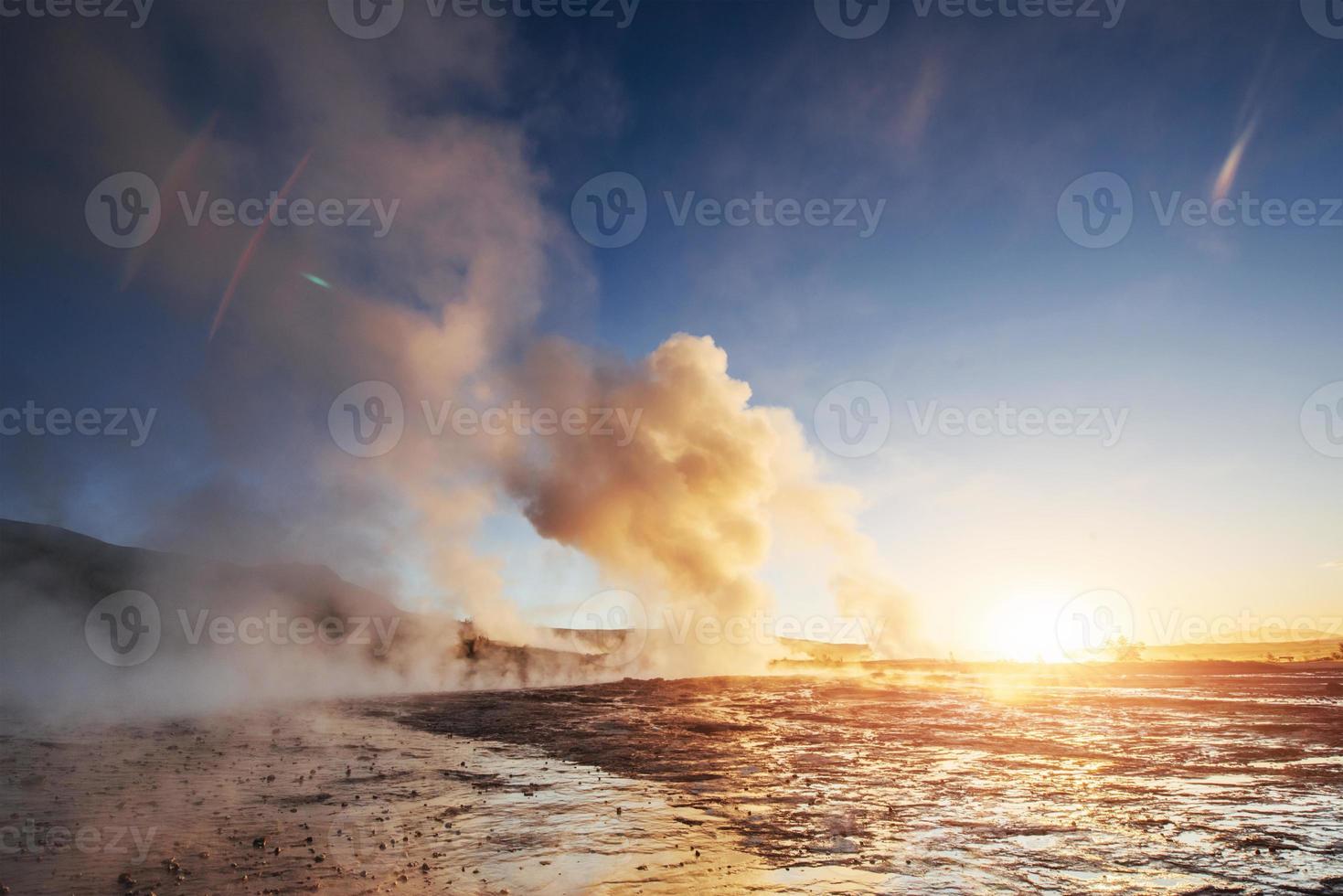 Erupción del géiser strokkur en islandia. colores fantásticos brillan a través del vapor. hermosas nubes rosadas en un cielo azul foto