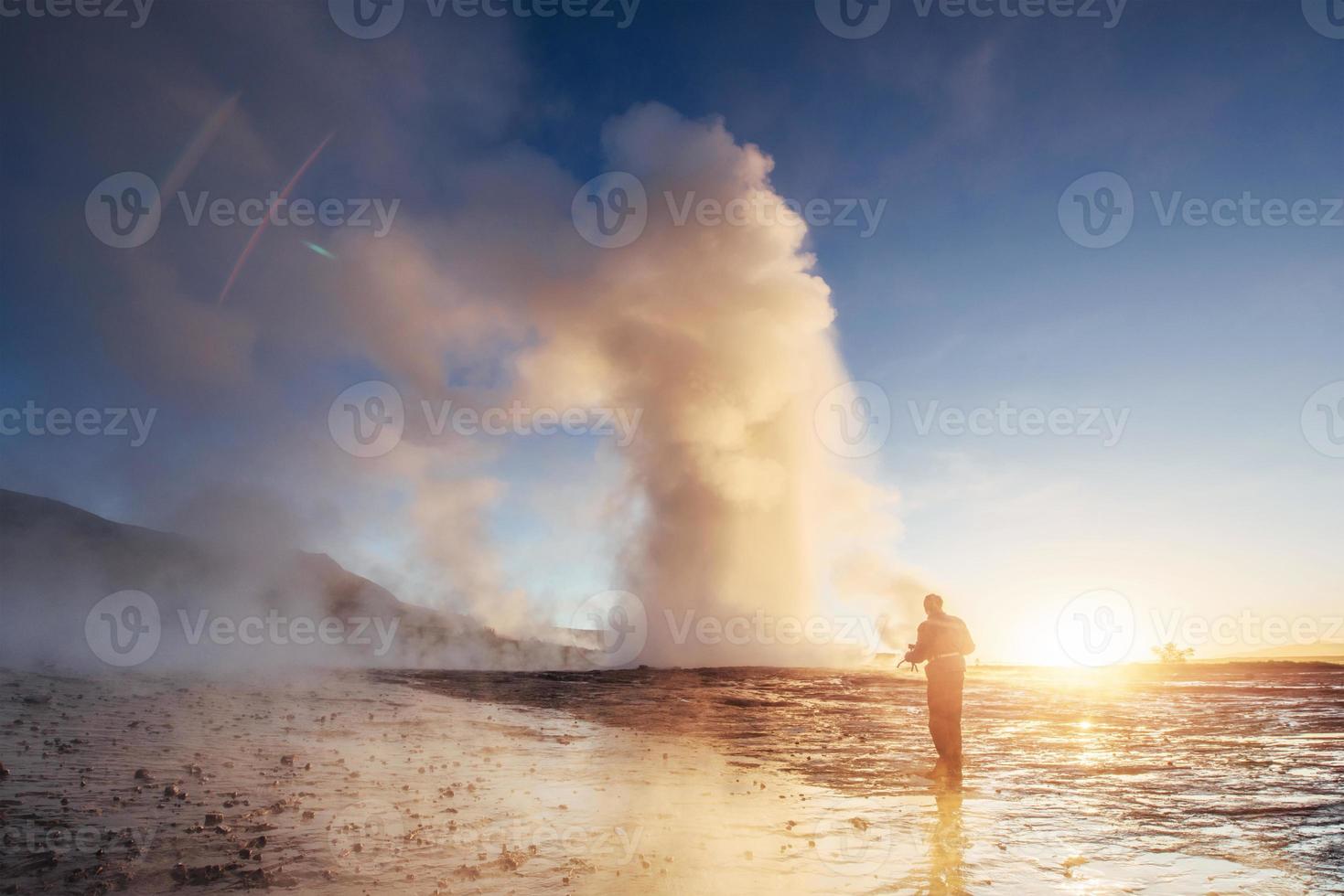 Eruption of Strokkur geyser in Iceland. Winter cold colors, sun lighting through the steam photo