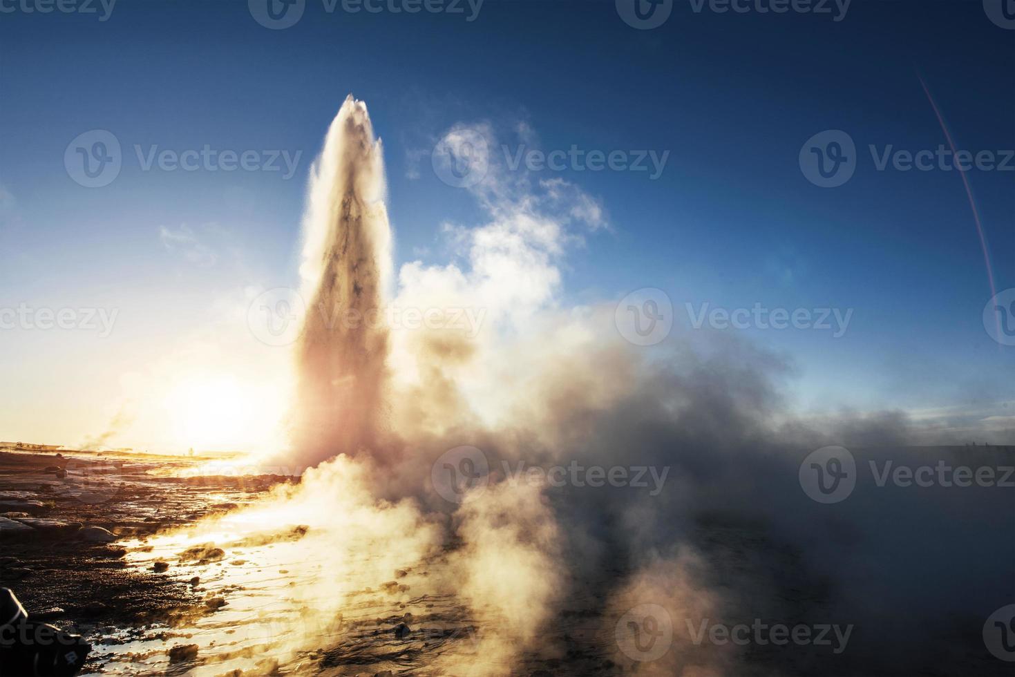 erupción del géiser strokkur en islandia. colores fríos de invierno, el sol se ilumina a través del vapor foto