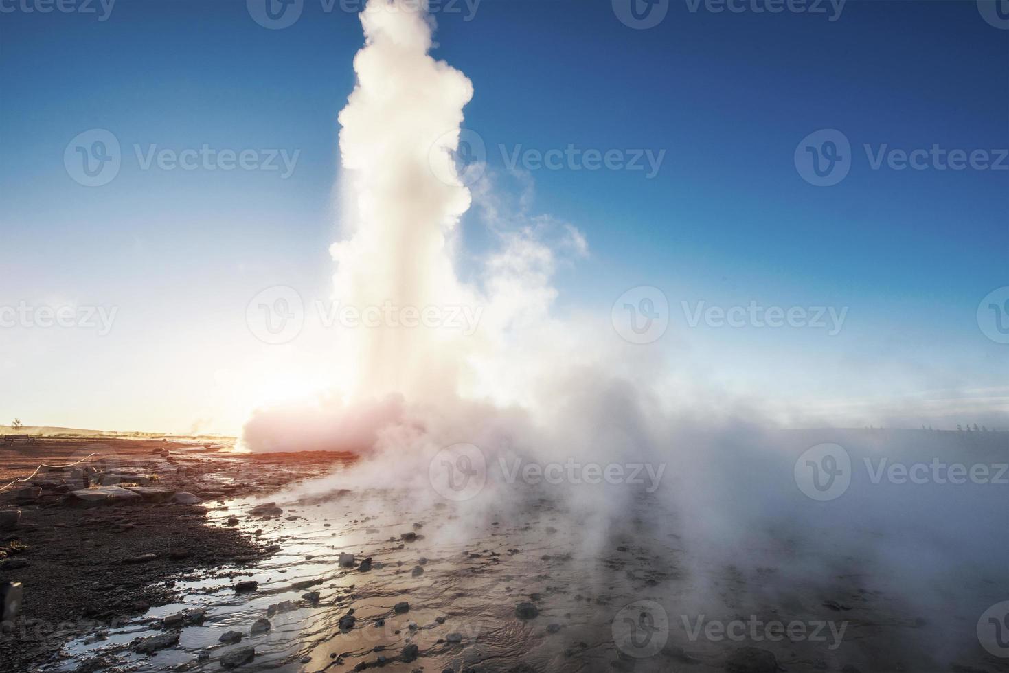 Strokkur geyser eruption in Iceland. Fantastic colors shine through the steam. Beautiful pink clouds in a blue sky photo