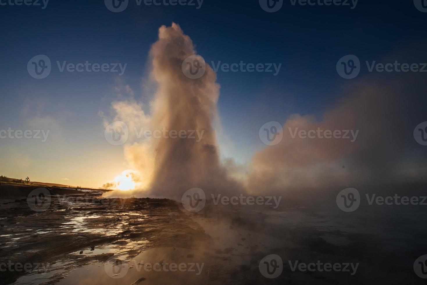 Strokkur geyser eruption in Iceland. Fantastic colors shine through the steam. Beautiful pink clouds in a blue sky photo