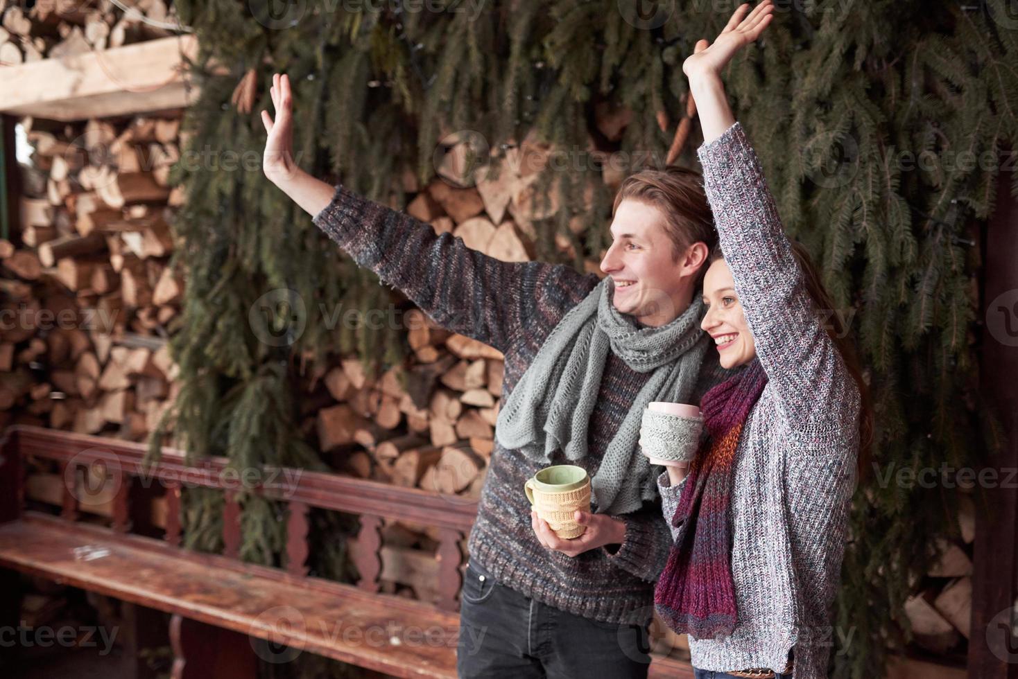 foto de hombre feliz y mujer bonita con tazas al aire libre en invierno. vacaciones de invierno y vacaciones. Pareja de Navidad de hombre y mujer felices beben café caliente. hola vecinos