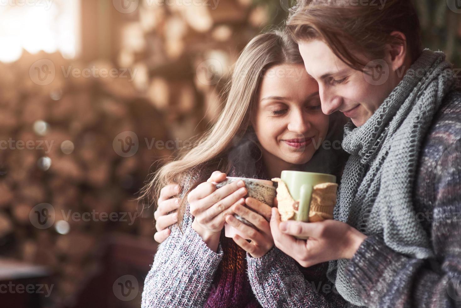 Young couple having breakfast in a romantic cabin outdoors in winter. Winter holiday and vacation. Christmas couple of happy man and woman drink hot wine. Couple in love photo