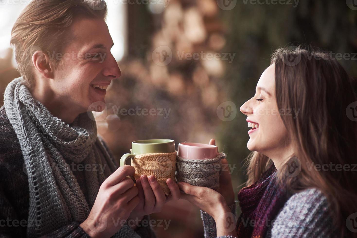 pareja joven desayunando en una cabaña romántica al aire libre en invierno. vacaciones de invierno y vacaciones. Pareja de Navidad de hombre y mujer felices beben vino caliente. pareja enamorada foto