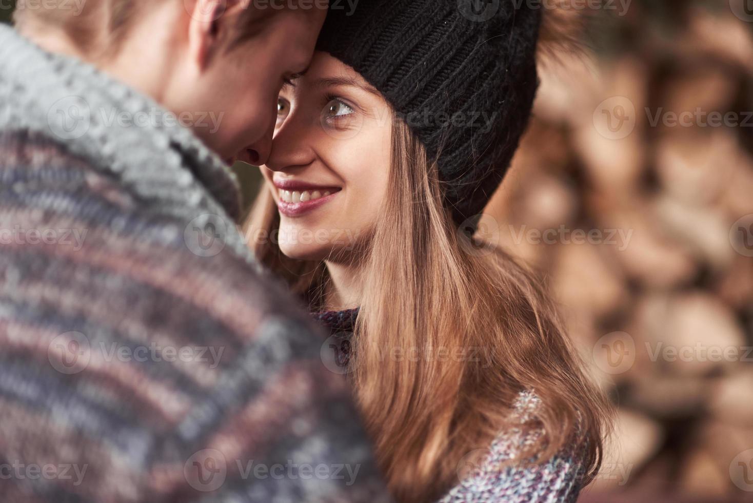 Waist up portrait of carefree young man and woman embracing and smiling. They are standing in winter forest and looking at camera with happiness photo