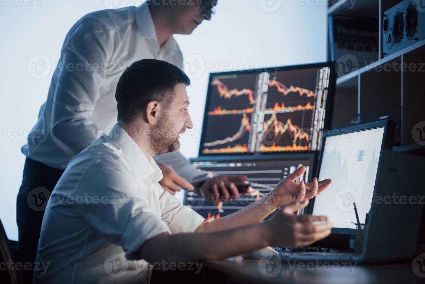 equipo de corredores de bolsa está conversando en una oficina oscura con pantallas de visualización. analizar datos, gráficos e informes con fines de inversión. comerciantes creativos de trabajo en equipo foto