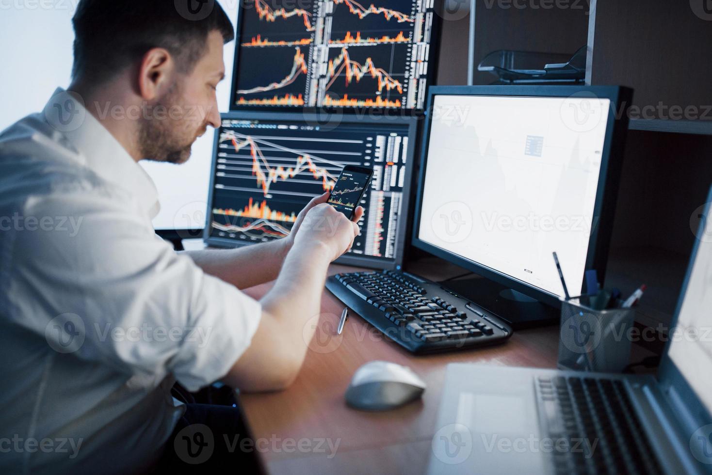 Stockbroker in shirt is working in a monitoring room with display screens. Stock Exchange Trading Forex Finance Graphic Concept. Businessmen trading stocks online photo