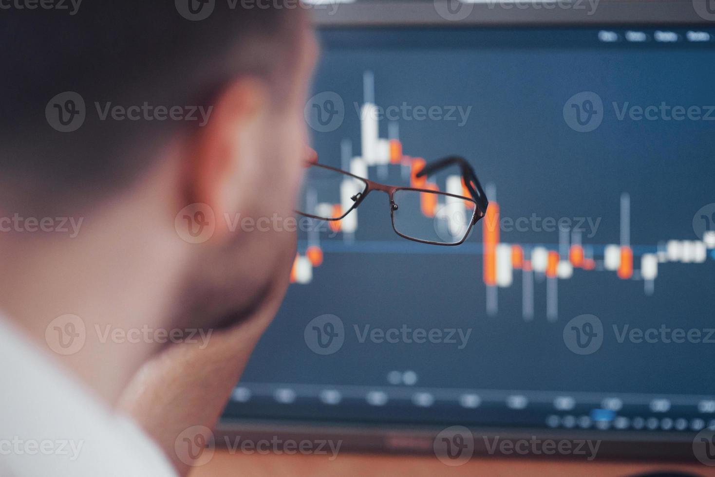 Analyzing data. Close-up of young businessman pointing on the data presented in the chart with pen while working in creative office photo