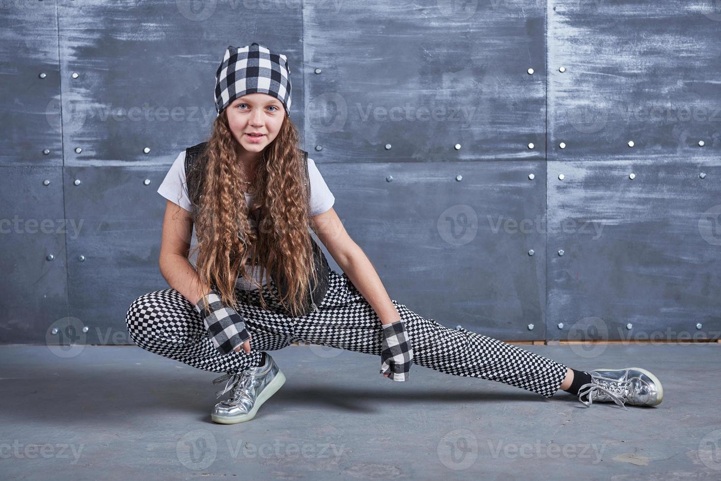 Young beautiful girl dancing in a trendy clothes on a grunge background photo