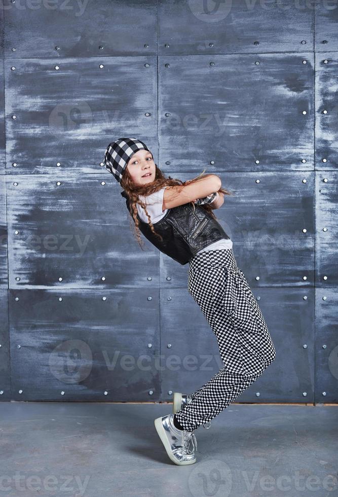 Hermosa joven bailando en ropa de moda sobre un fondo grunge foto