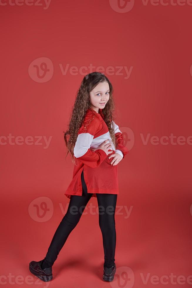 Joven hermosa linda chica bailando sobre fondo rojo, moderno y delgado estilo hip-hop adolescente saltando foto