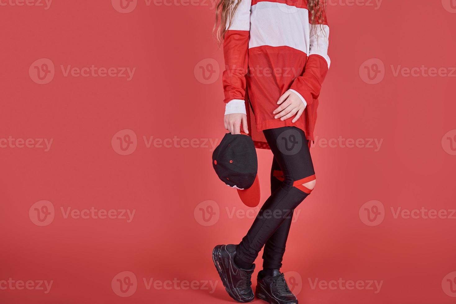 Young urban woman dancing on red background, modern slim hip-hop style teenage girl photo