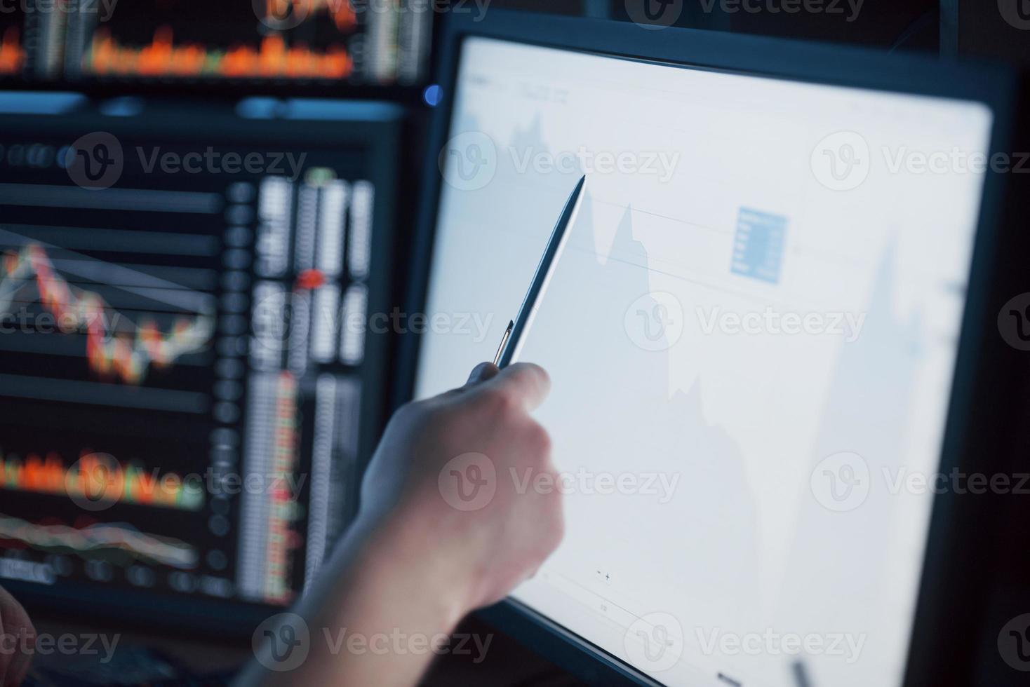 Analyzing data. Close-up of young businessman pointing on the data presented in the chart with pen while working in creative office photo