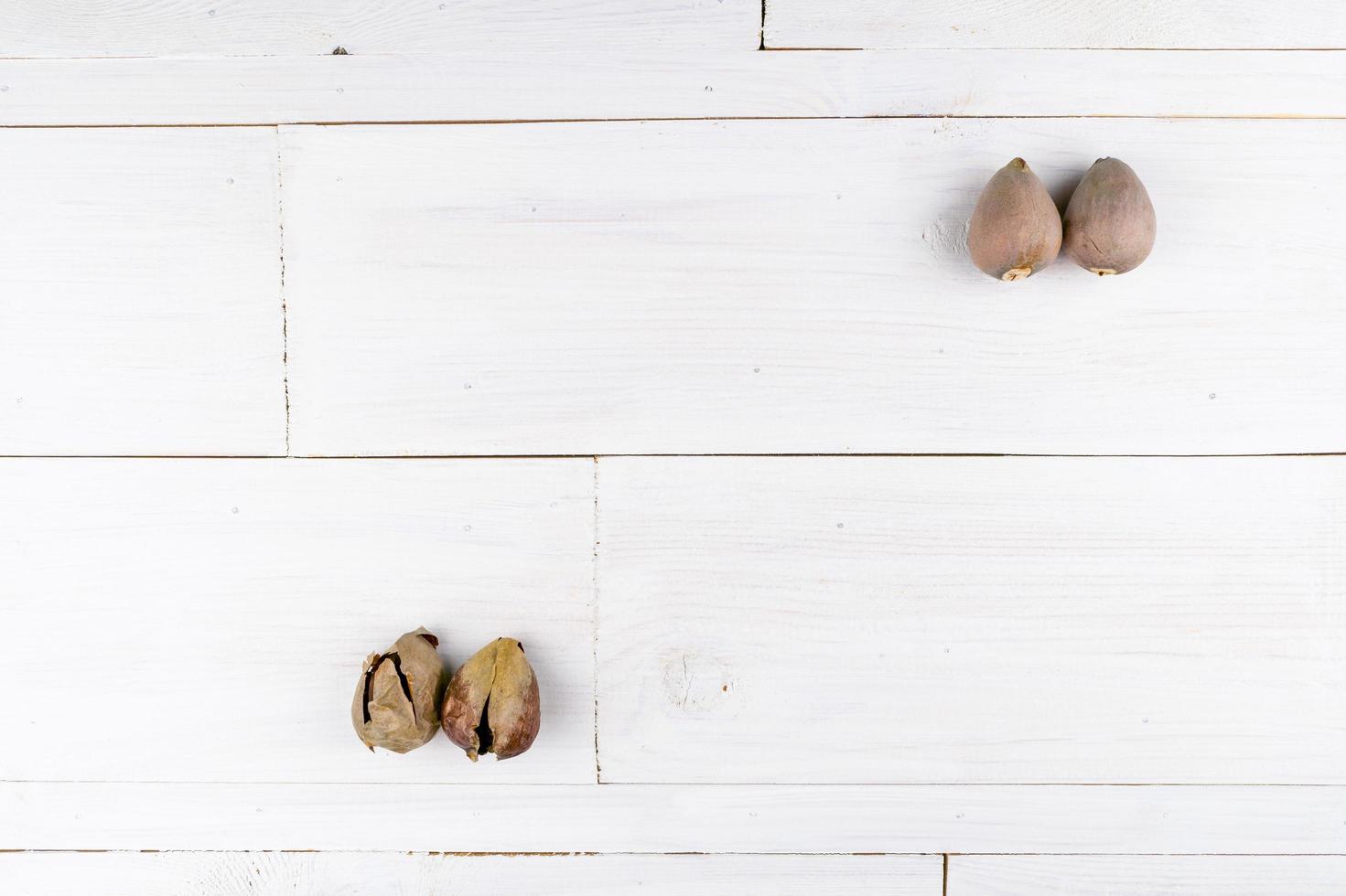 Dos granos de aguacate fresco y dos granos rotos en la mesa de madera foto