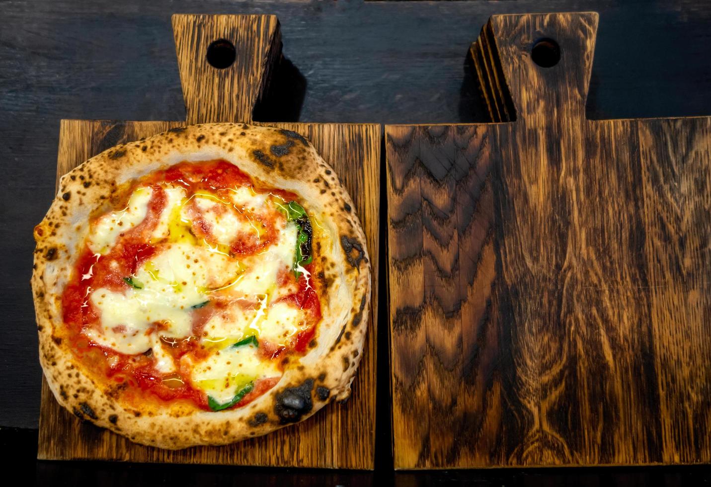 Neapolitan pizza on a dark wooden chopping board photo