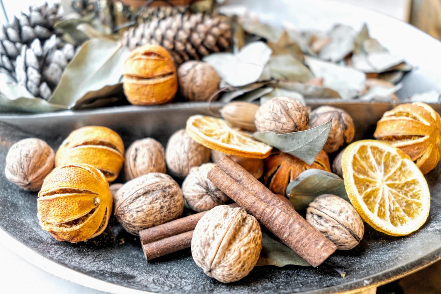 Dehydrated fruits, walnuts, and cones in a wide decorative vase photo