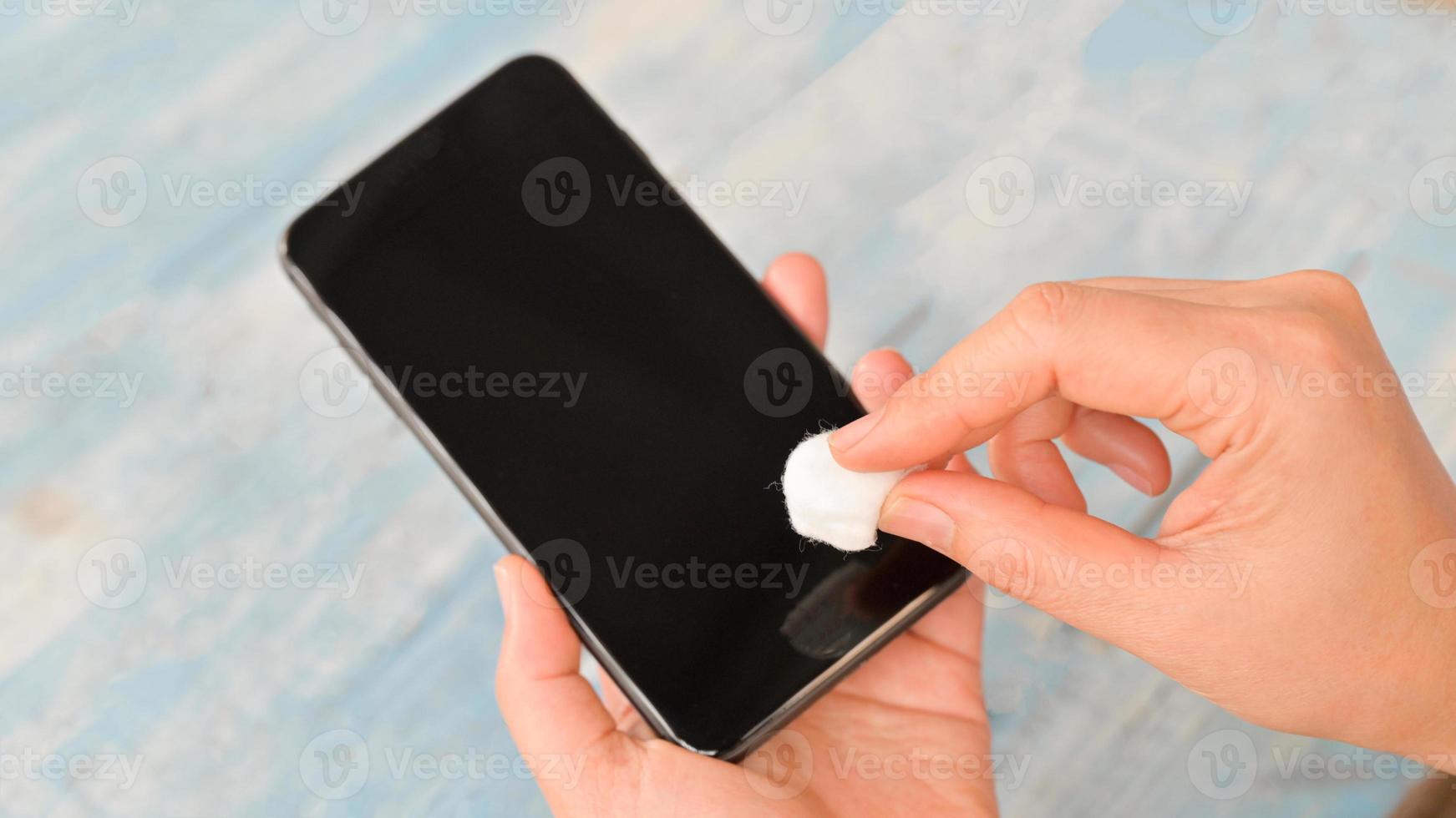 Close-up shot of Spray and wipe the alcohol to clean and kill germs on the smartphone. photo