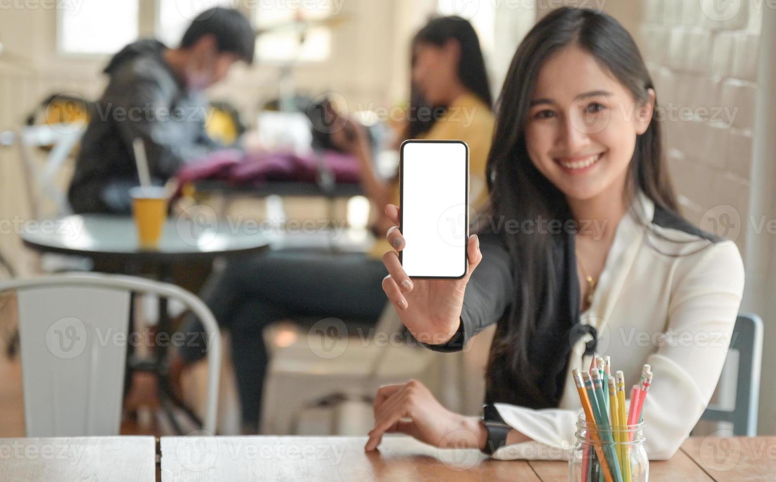 Cropped shot of a Woman holding a blank screen smartphone to the front.She offers a insurance package to cover virus infection. photo