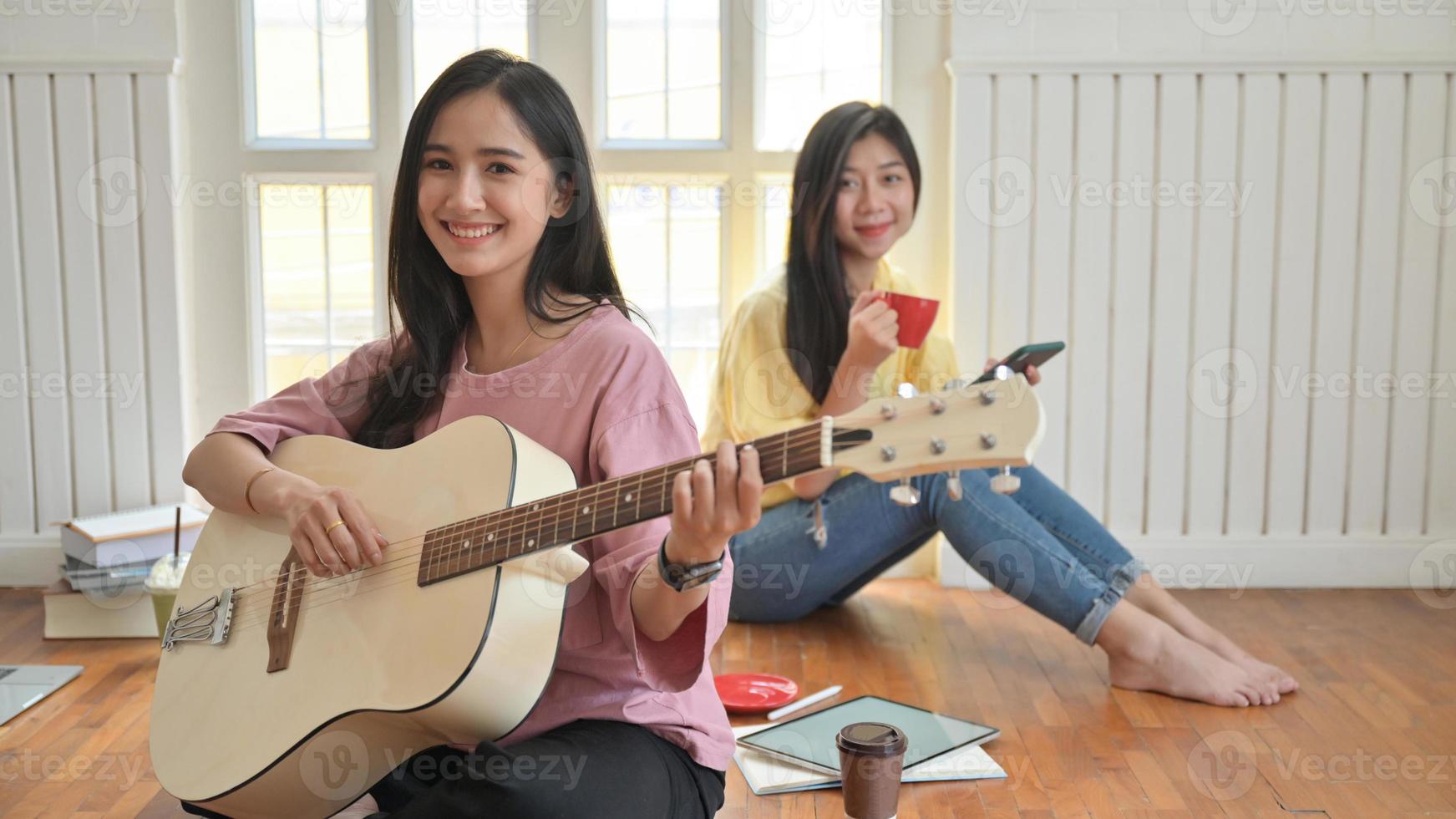 Las adolescentes asiáticas cantan y tocan guitarras. Se quedan en casa para prevenir el brote del virus corona. foto
