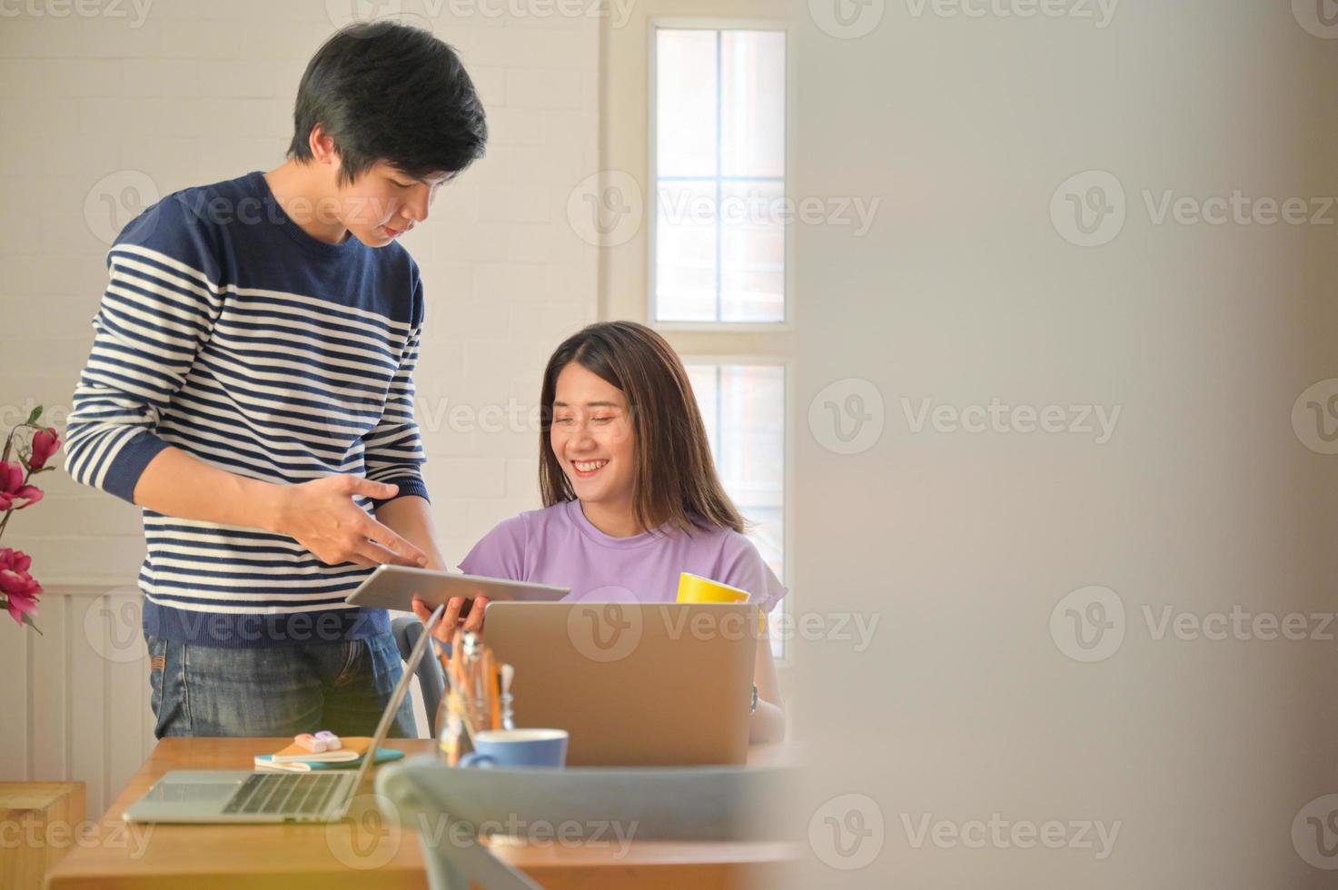 estudiantes masculinos y femeninos están consultando proyectos para presentaciones de maestros con tabletas y computadoras portátiles. foto