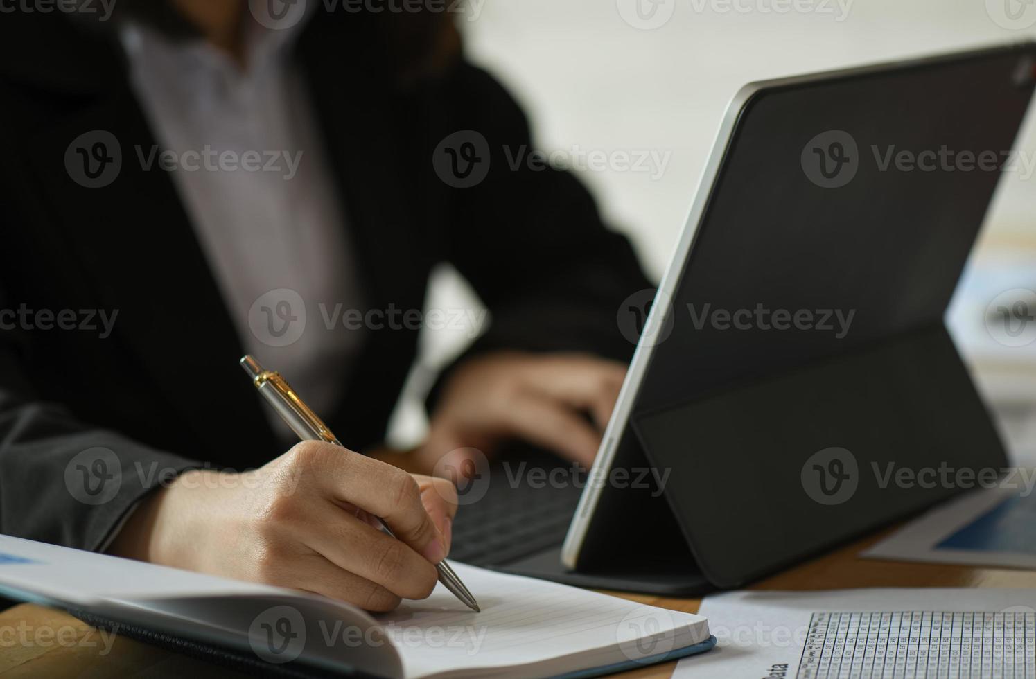 Las mujeres empresarias están usando la computadora portátil y tomando notas del trabajo en el escritorio de la oficina. foto