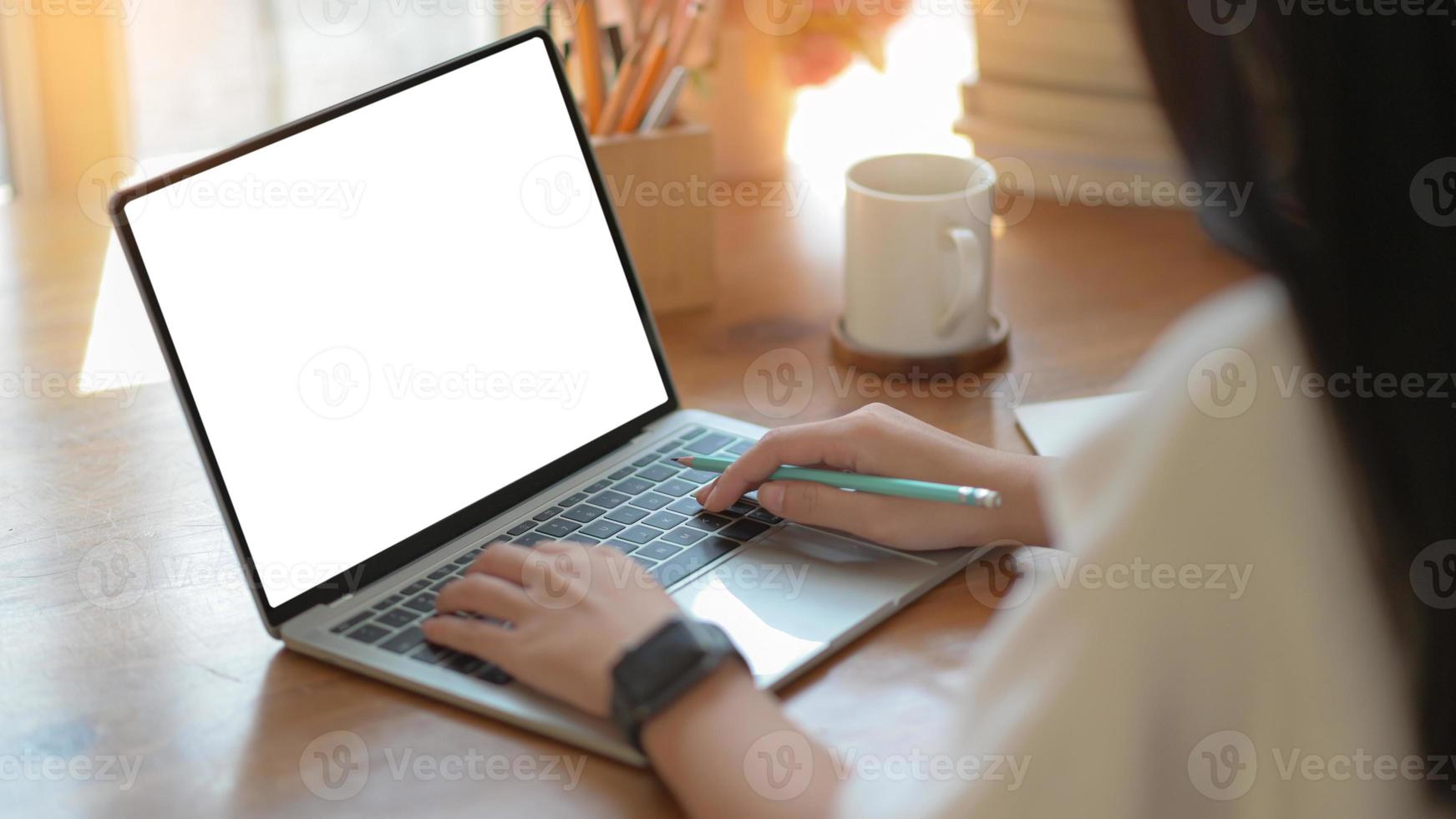 Las mujeres de negocios jóvenes están utilizando un portátil de pantalla en blanco con una taza de café en la oficina moderna. foto