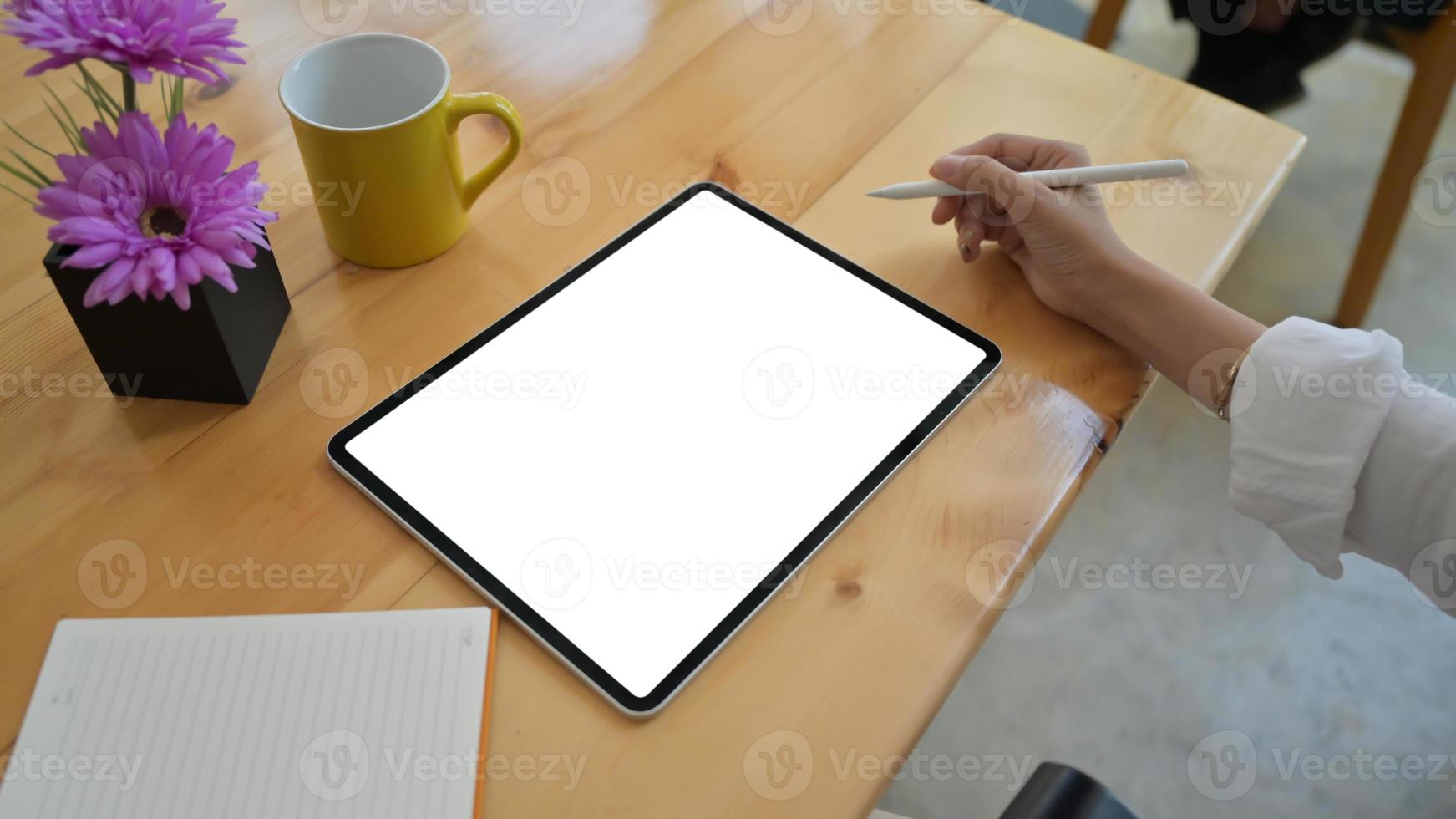 primer plano de una niña sosteniendo un bolígrafo y usando una tableta de pantalla en blanco. foto