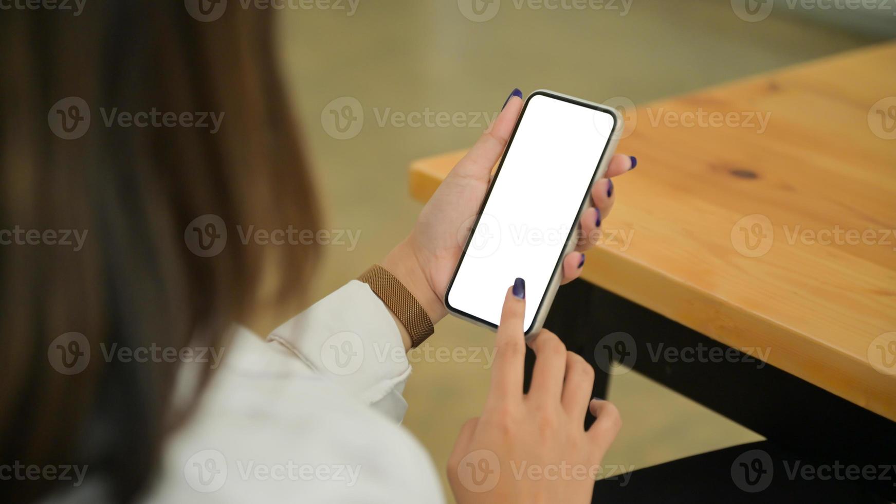 primer plano de mujer joven sostiene y utiliza el teléfono inteligente de pantalla en blanco. foto