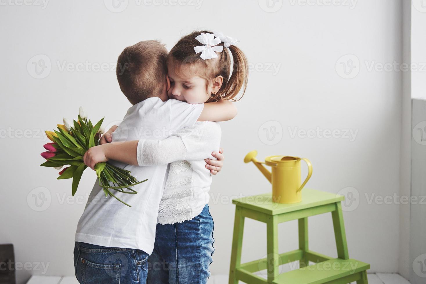 hermoso niño y niña con tulipanes con abrazo. día de la madre, 8 de marzo, feliz cumpleaños foto