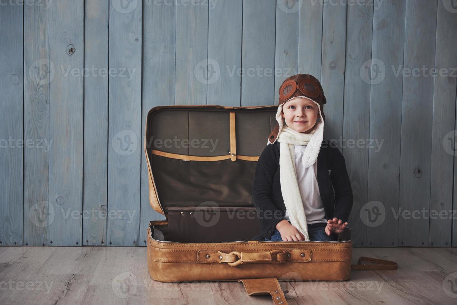 Happy kid in pilot hat playing with old suitcase. Childhood. Fantasy, imagination. Holiday photo