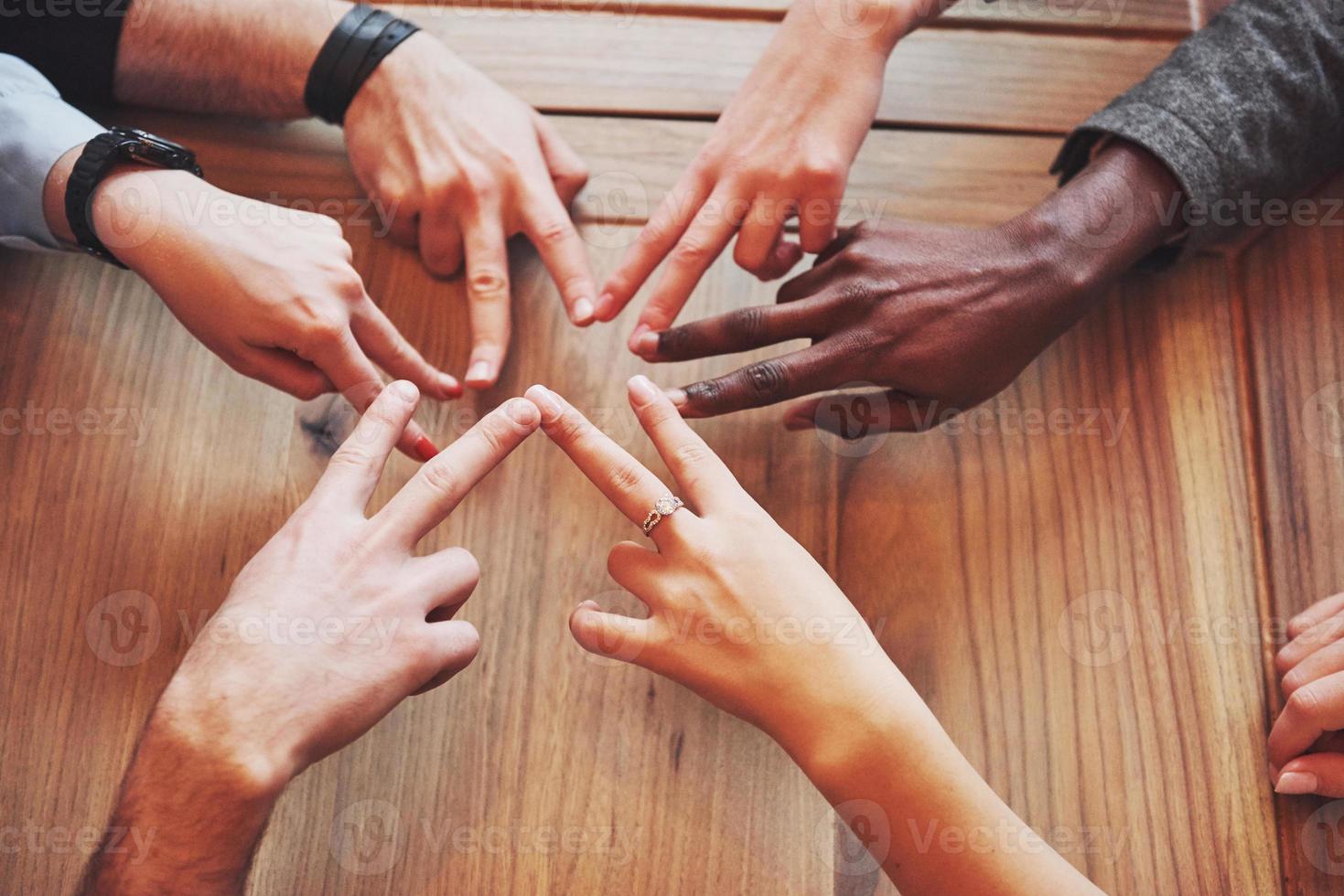 Close up top view of young people putting their hands together. Friends Doing a Star Shape with fingers showing unity and teamwork photo