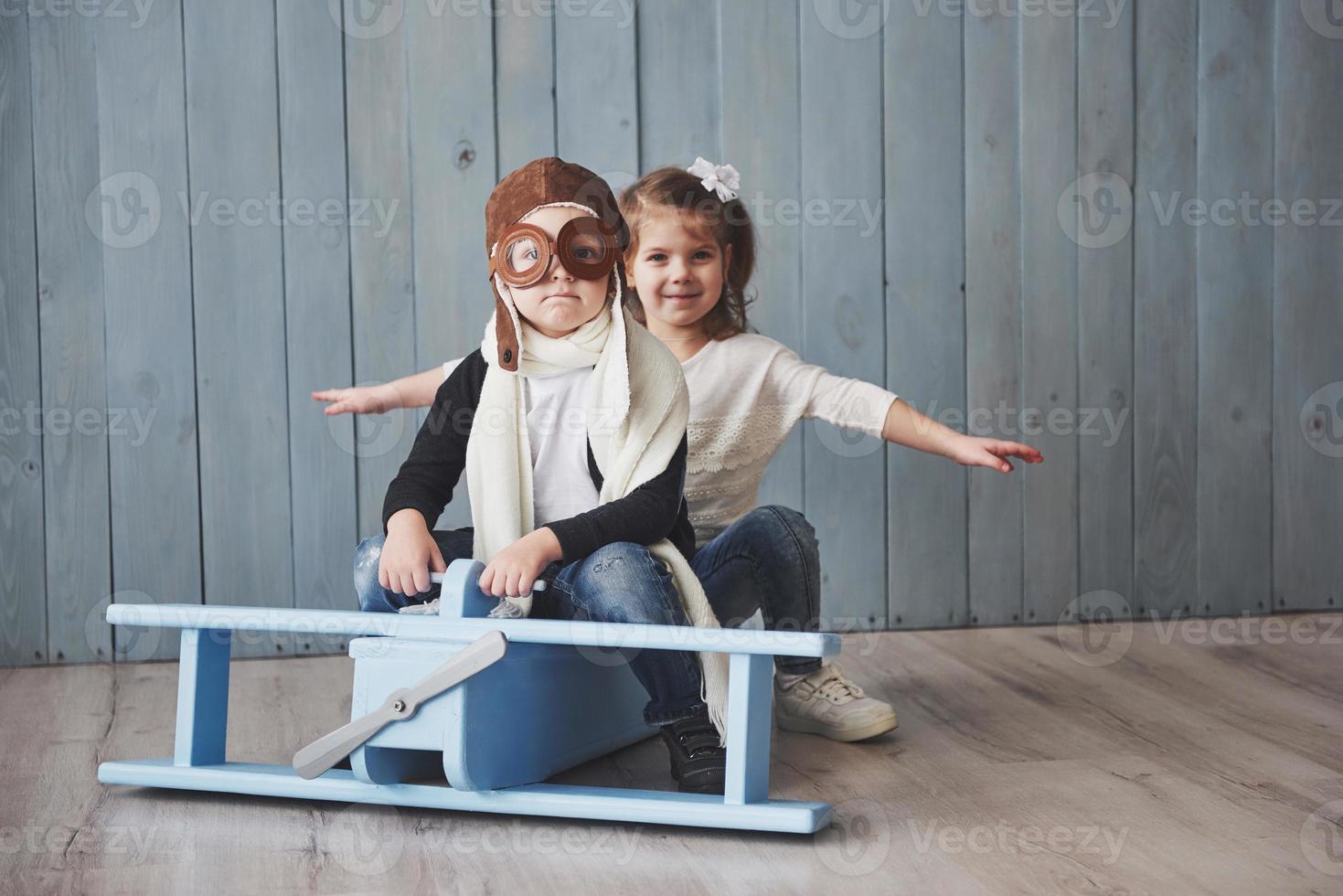 Happy kid in pilot hat playing with wooden airplane against. Childhood. Fantasy, imagination. Holiday photo