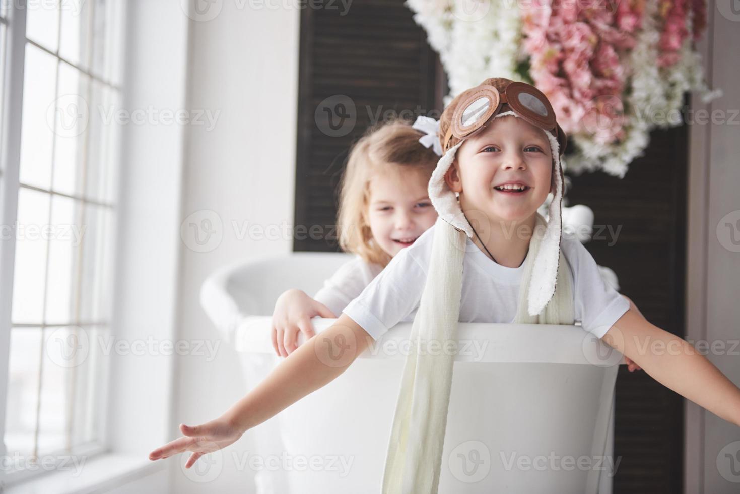 Portrait of a girl and a boy in pilot hat playing in bathroom at pilots or sailors. The concept of travel, childhood and the realization of dreams photo