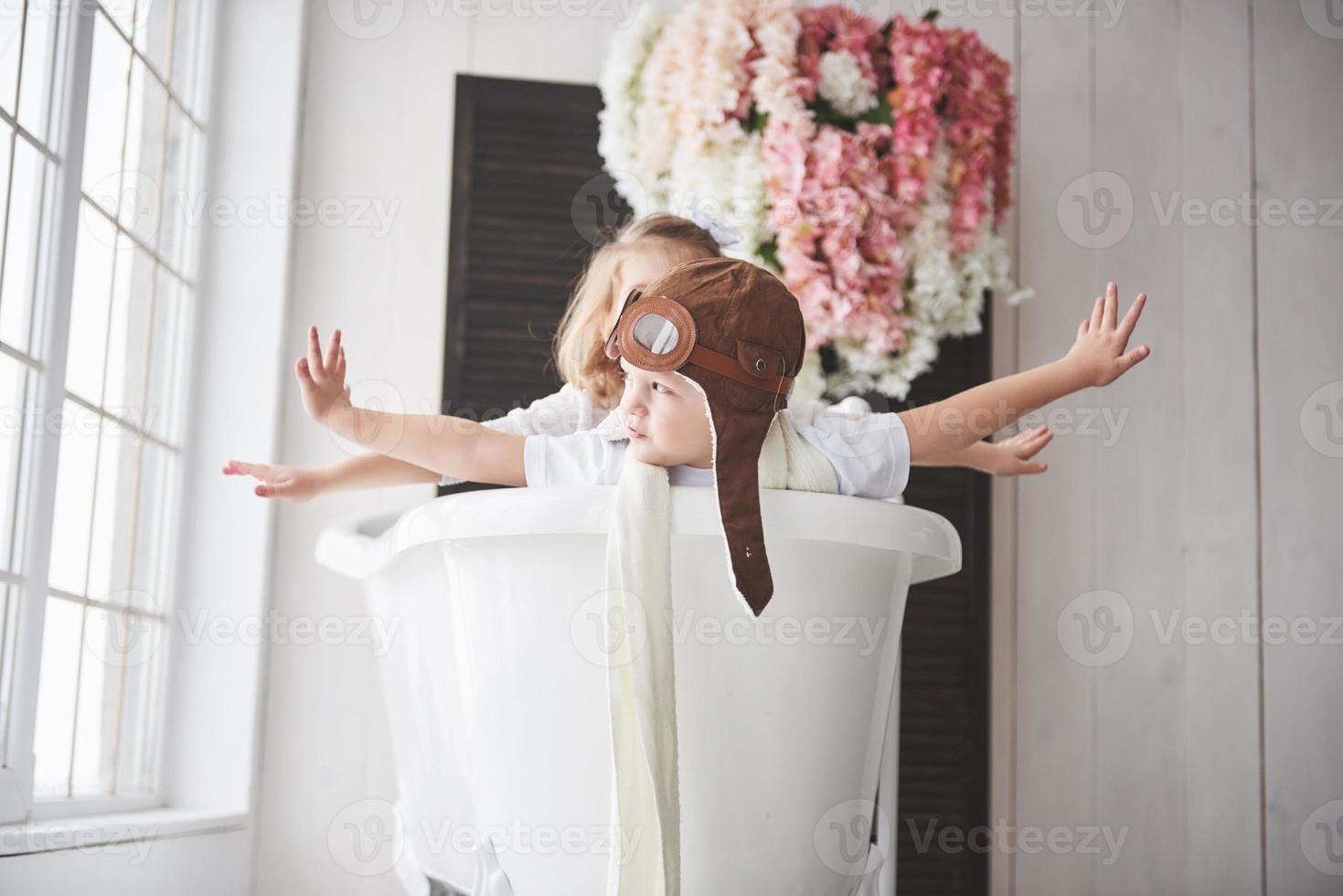 Portrait of a girl and a boy in pilot hat playing in bathroom at pilots or sailors. The concept of travel, childhood and the realization of dreams photo