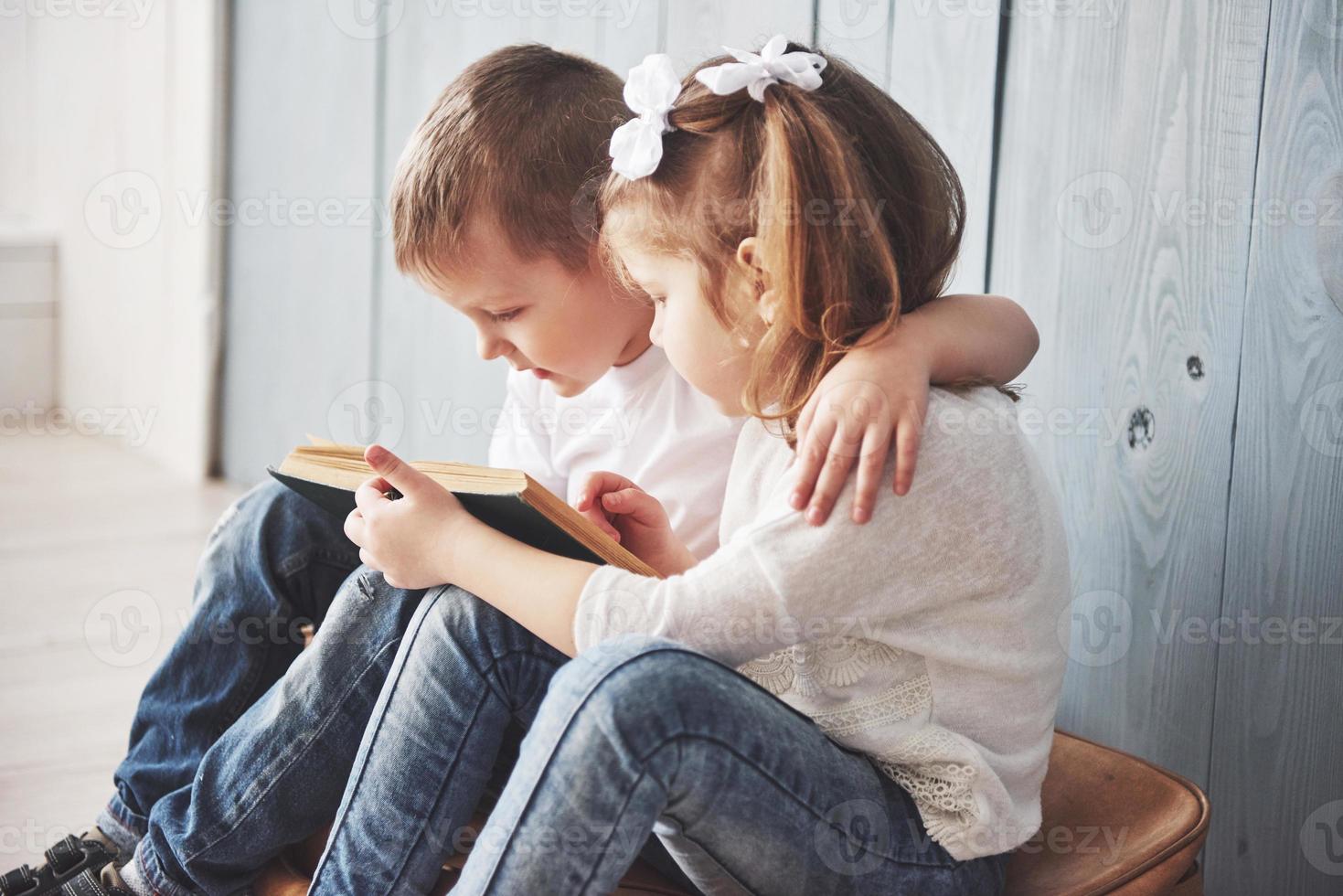 listo para grandes viajes. feliz niña y niño leyendo un libro interesante con un maletín grande y sonriendo. concepto de viaje, libertad e imaginación. foto