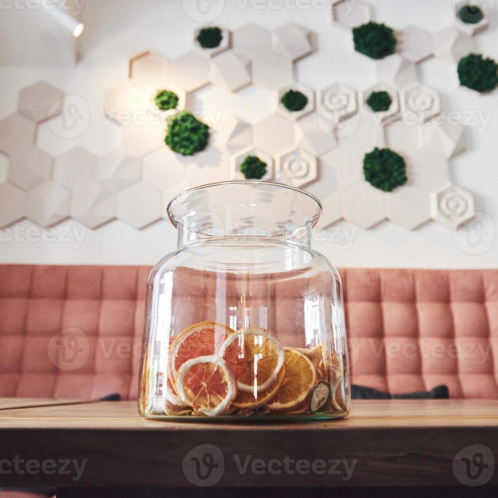 Dried candied orange, lime and lemon wheels in large glass container with contents also arranged on butcher block around jar with raw sugar and metal lid photo