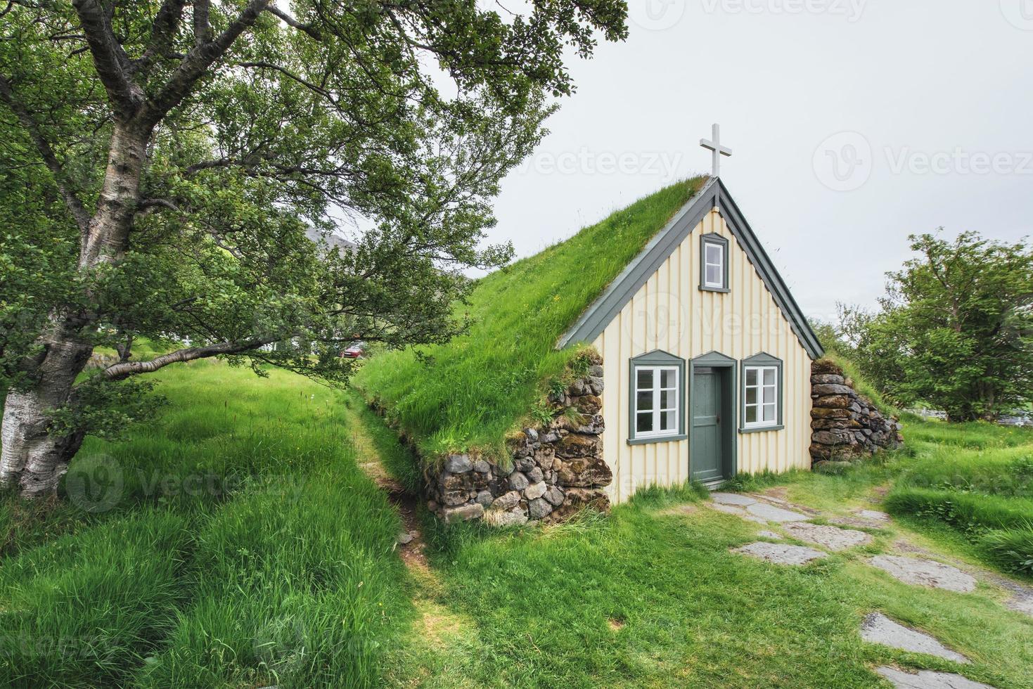 una pequeña iglesia de madera y cementerio hofskirkja hof, skaftafell islandia. puesta de sol escénica a través de las copas de los árboles foto