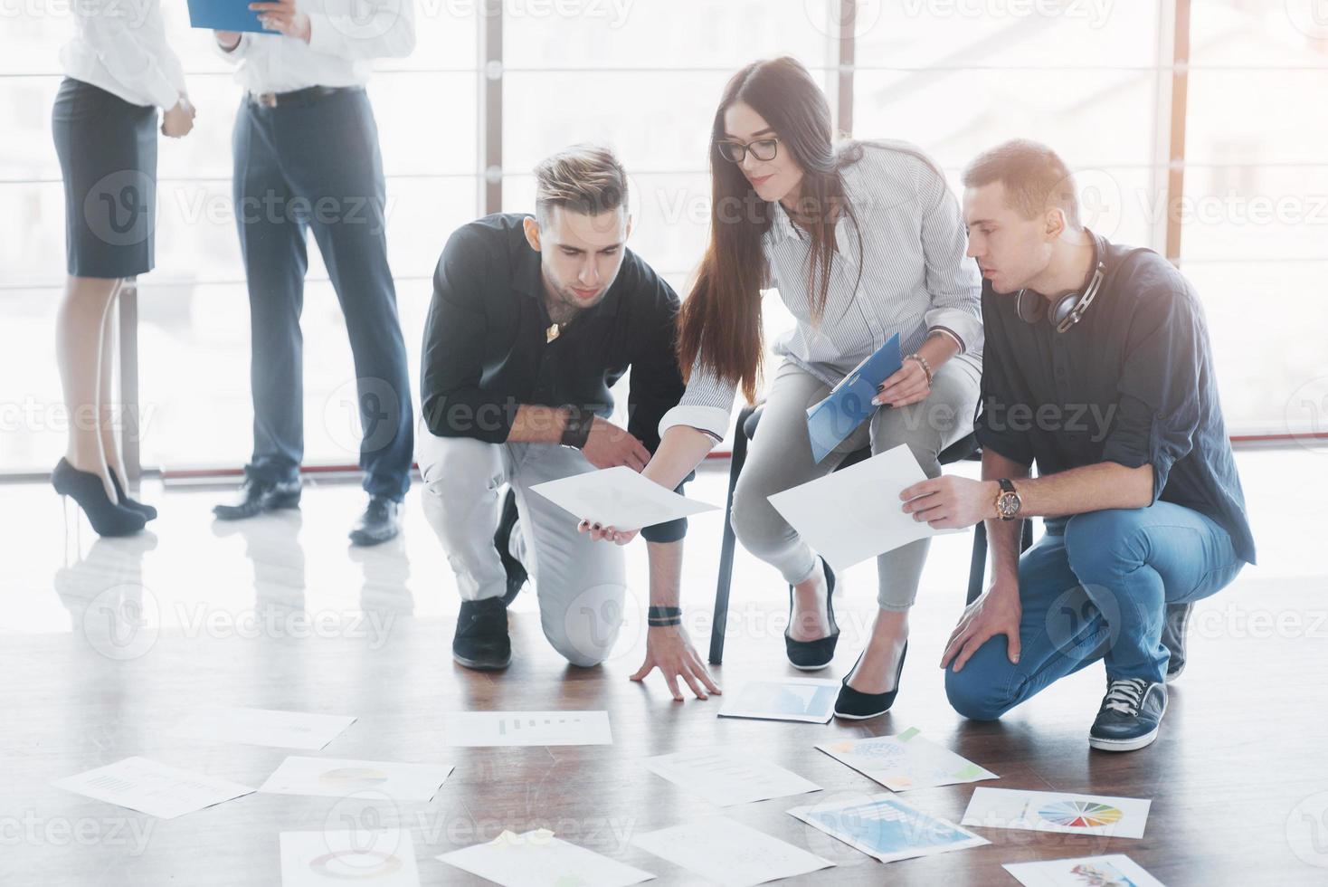 Young creative people in modern office. Group of young business people are working together with laptop. Freelancers sitting on the floor. Cooperation corporate achievement. Teamwork concept photo