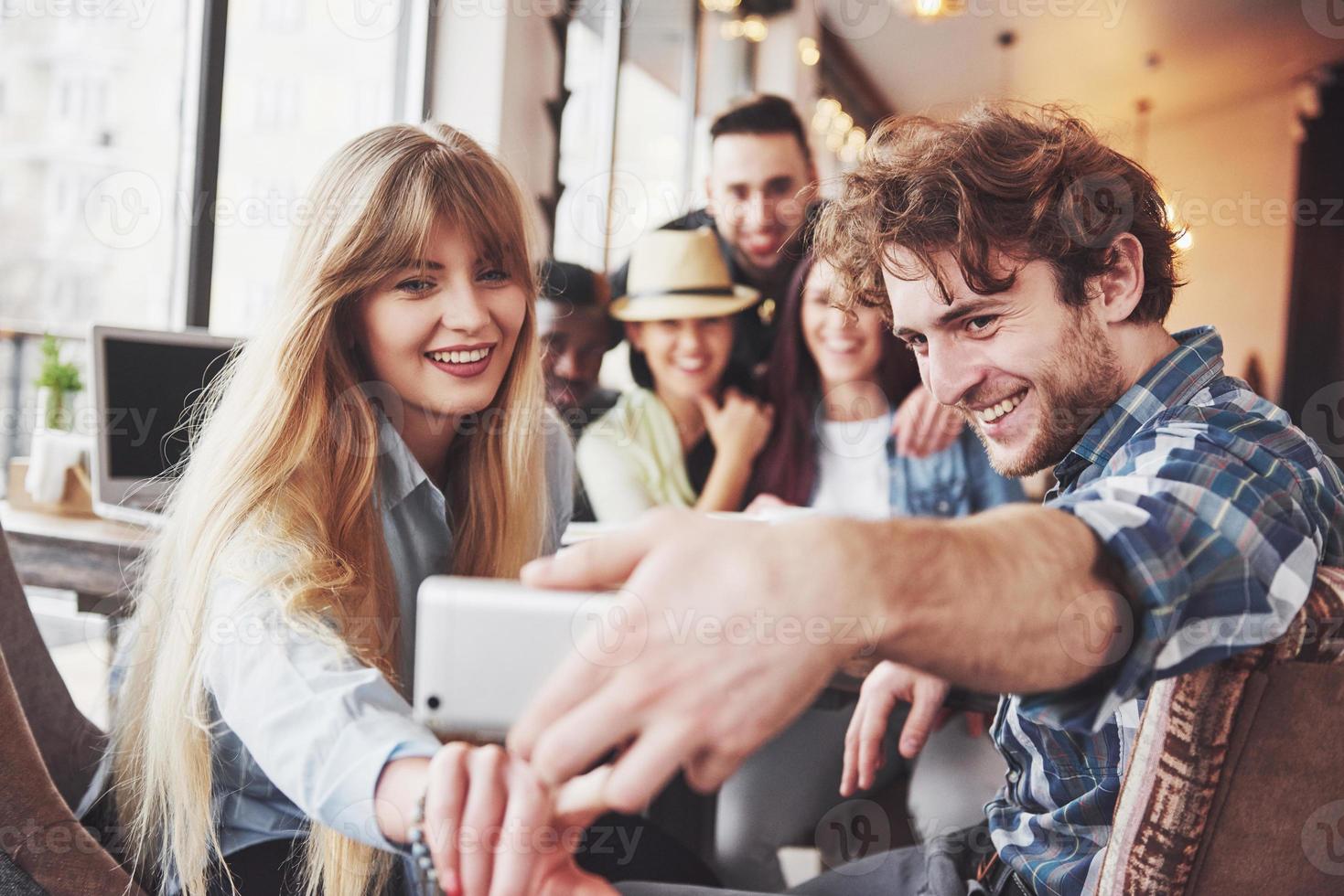 Self portrait of mixed race unity of african, american, asian, caucasian friends, happy bearded men and beautiful women in red santa hat showing thumb up, like, ok gesture to the camera in office photo